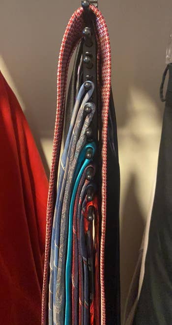 reviewer's various ties on the hanger in a closet, showing the slim, space-saving design