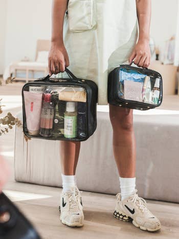 model holding the mini and regular sized toiletry bags