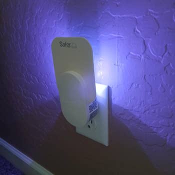 Plug-in pest repeller device on a wall outlet, emitting a soft glow
