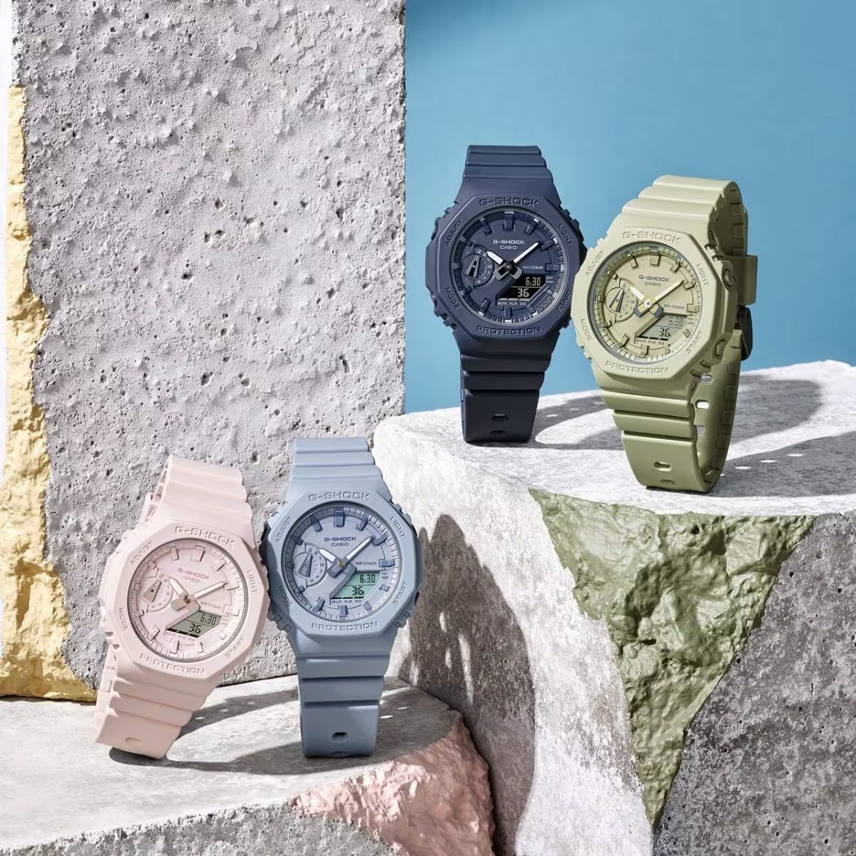 four g-shock watches in light pink, light blue, green, and black