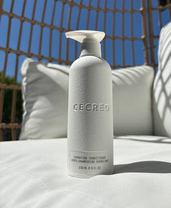 Bottle of CÉCRED hydrating conditioner connected  an outdoor lounge chair