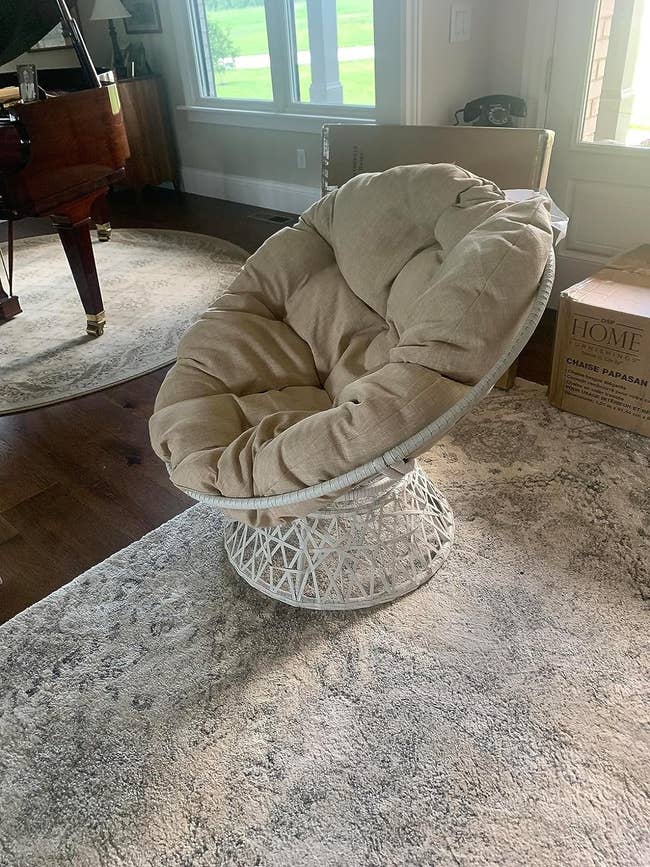 Papasan chair with a cushion on a rug in a home interior