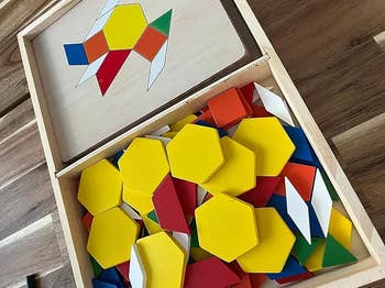 Wooden container of colorful geometric signifier blocks for originative play, learning, and acquisition activities