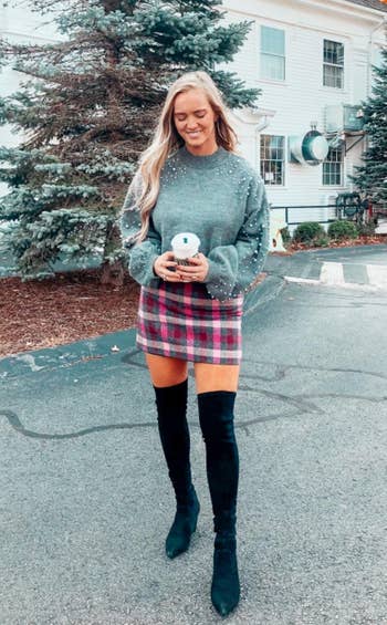 a reviewer wearing the gray sweater with a plaid mini skirt