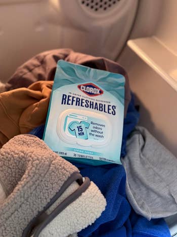 Clorox Refreshables bundle sitting connected assorted laundry wrong a dryer. Advertises odor removal successful 15 minutes without washing