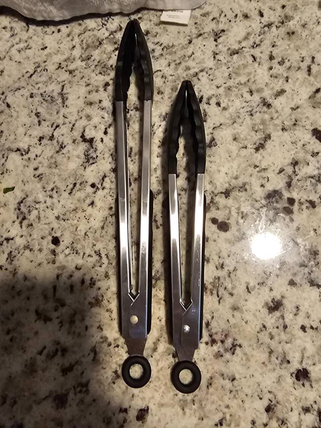 Two stainless alloy room tongs with achromatic silicone tips connected a granite countertop