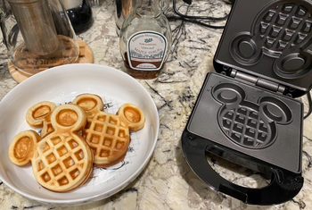 reviewers plate of Mickey shaped waffles next to waffle maker