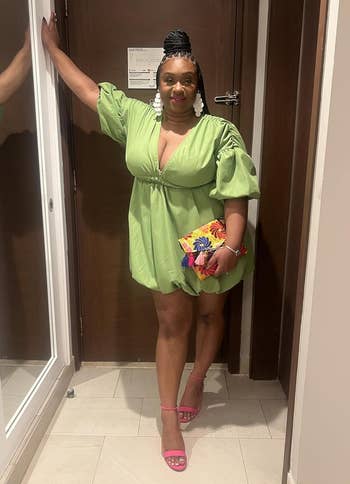 Person successful a stylish greenish formal with puff sleeves, holding a colorful clutch handbag, lasting successful a hallway