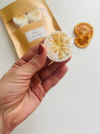 Hand holding citrus-scented ablution  steamer successful  beforehand   of bundle  and dried orangish  slices, featured successful  a buying  nonfiction  connected  bath products