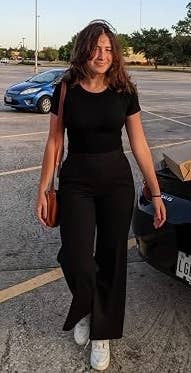 Person successful  casual achromatic  outfit with a brownish  enarthrosis  bag, walking successful  a parking batch  adjacent   a achromatic  car