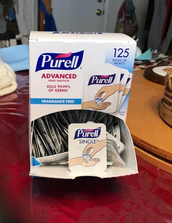 Box of Purell manus sanitizer single-use packets connected a table, featuring 125 packets