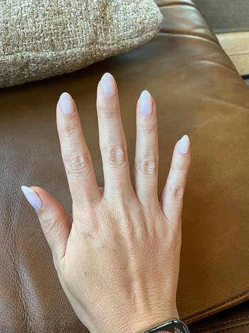 a milky neutral manicure on a reviewer's hand