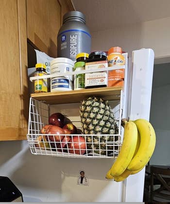 Kitchen support  with supplements, a ample  h2o  vessel  connected  top, and a handbasket  holding apples, a pineapple, and bananas hanging outside