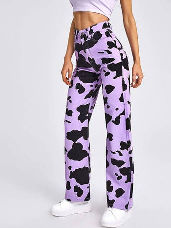 a model wearing the cow print pants in purple