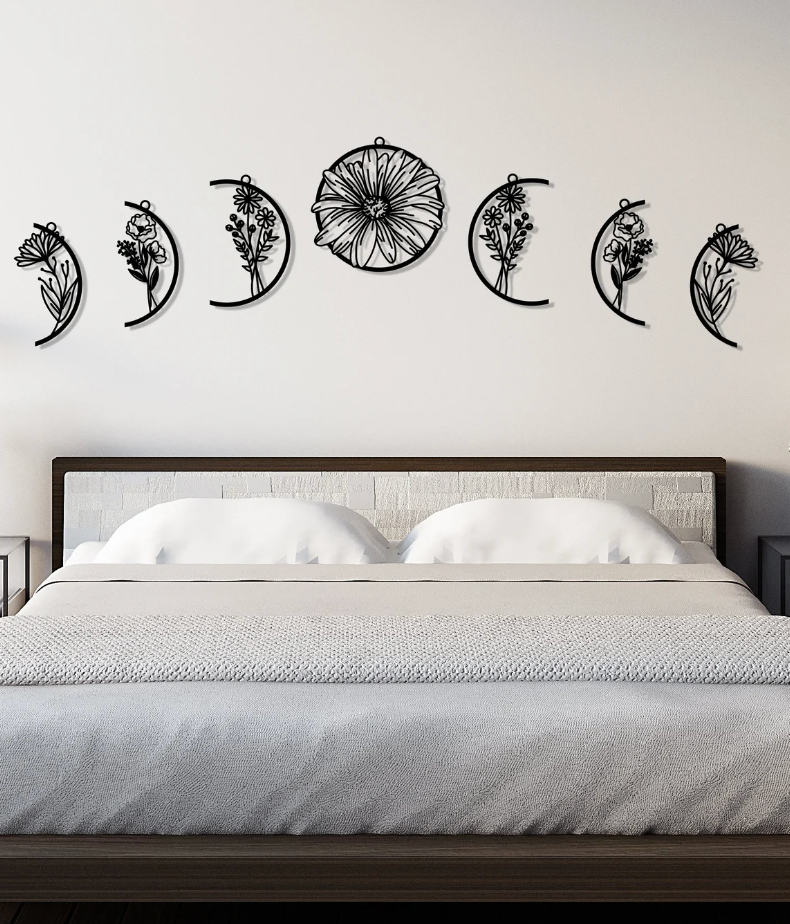 Black floral moon phase wall decals hanging above a bed