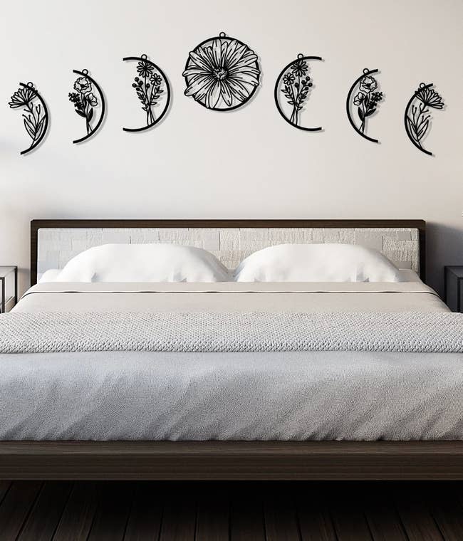 Black floral moon phase wall decals hanging above a bed