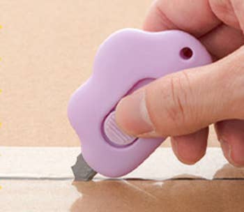Model using a purple cloud shaped knife to open a package 