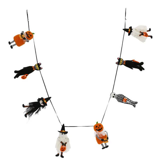 Halloween-themed garland with tiny  witch, skeleton, and pumpkin figures hanging connected  a string