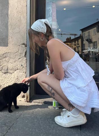 reviewer petting a feline portion wearing the achromatic sneakers