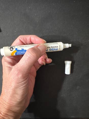 Hand holding a stain remover pen with its cap off