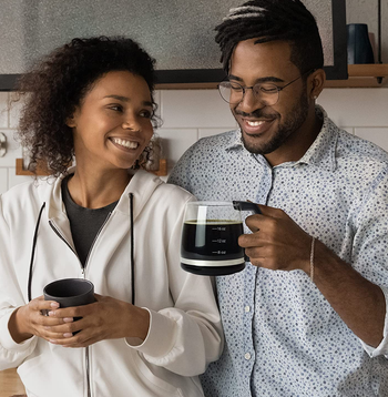 two models, one of whom is holding the coffee-filled mug