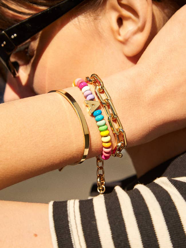 model wearing colorful bead bracelet with gold letter stacked with other bracelets