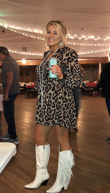 Reviewer wearing white knee high cowboy boots with fringe on the outer side