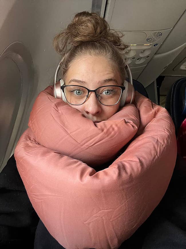 Reviewer wearing terracota-colored scarf-like pillow astir their cervix