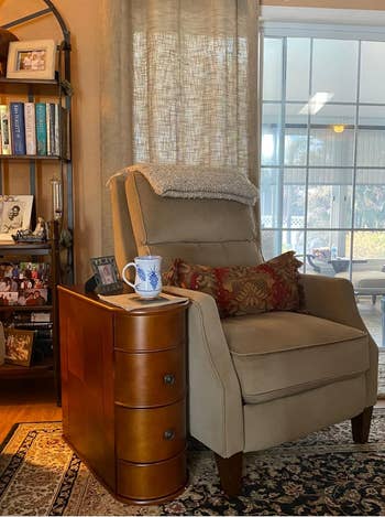 Cozy speechmaking  nook with an armchair, a woody  broadside  array  with a mug, books connected  a shelf, and household  photos. Warm and inviting location  decor setting