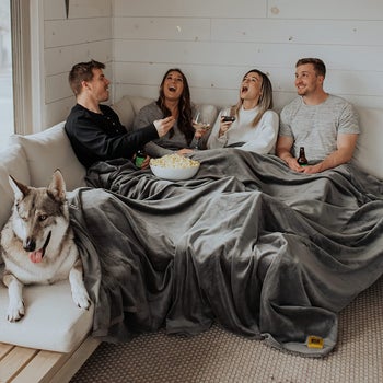 Four models drinking and eating popcorn under the grey blanket