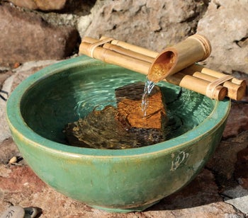 the bamboo fountain placed over a green pot filled with water
