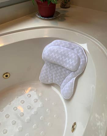 reviewer photo of the bath pillow in a bathtub