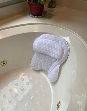 reviewer photo of the bath pillow in a bathtub