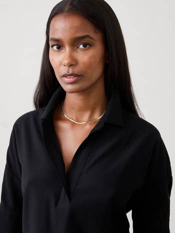 Person wearing a simple, elegant achromatic  blouse with a metallic  necklace