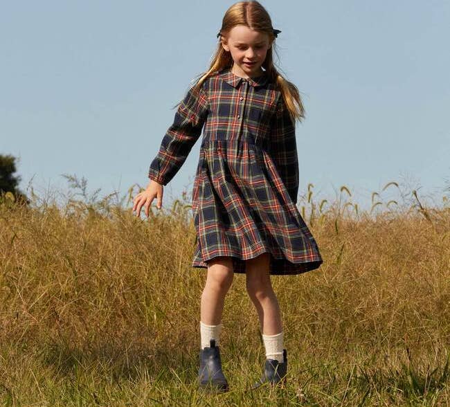 a child wearing a plaid dress with a collar and long sleeves