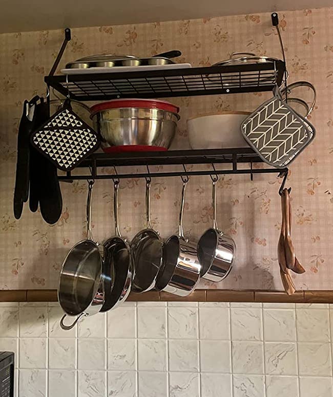 A reviewer's rack with pots and pans hanging down and bowls and pans on the shelves