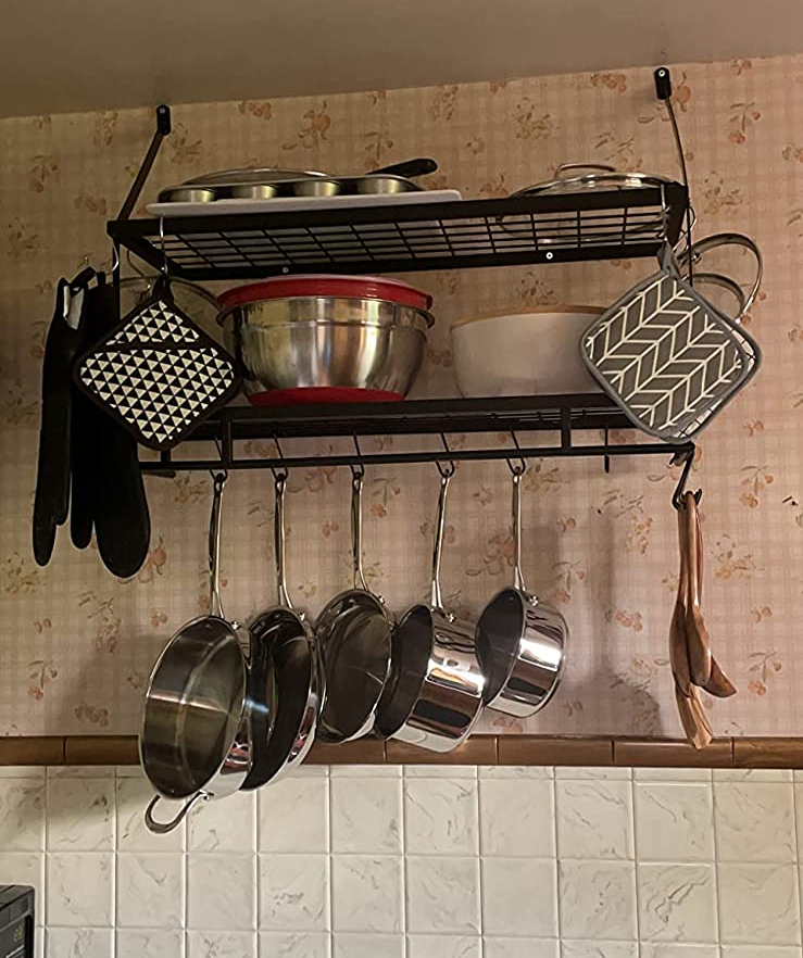 A reviewer's rack with pots and pans hanging down and bowls and pans on the shelves