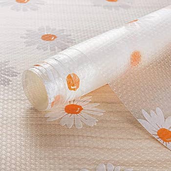 Roll of floral patterned plastic tablecloth on a textured surface