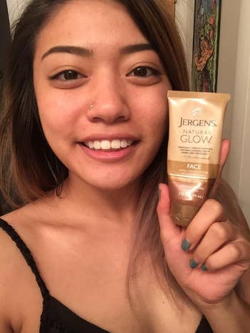 reviewer with glowy complexion holds container of the moisturizer