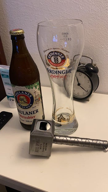 reviewer photo of the hammer bottle opener next to a bottle of beer and a glass