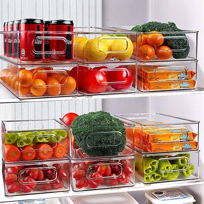 A fridge with transparent organizing bins filled with fruits, vegetables, snacks, and drinks