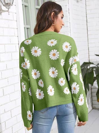 Person in a green sweater with white daisy patterns