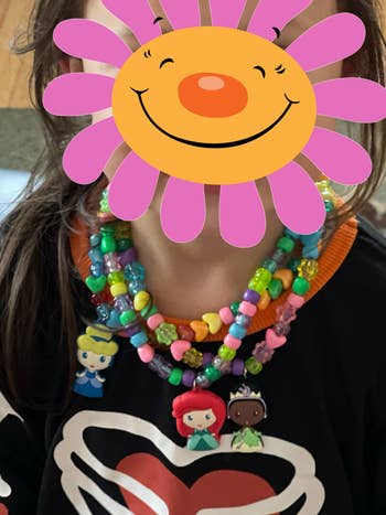 reviewer's child wearing three of the Disney princess necklaces they designed with colorful beads