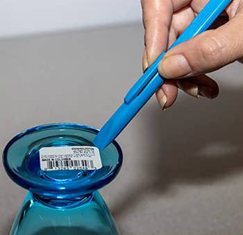 The same scraper tool being used to remove a sticker from a drinking glass