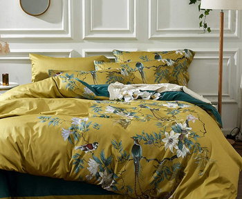 a light green duvet with a peacock print and matching pillows 