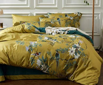 a light green duvet with a peacock print and matching pillows 