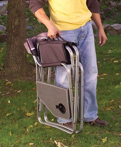 person carrying the folded black camper chair
