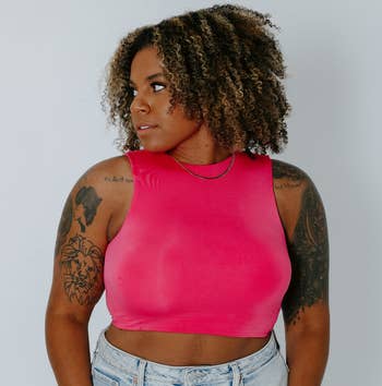 a model wearing a high neck cropped tank top in bright pink 
