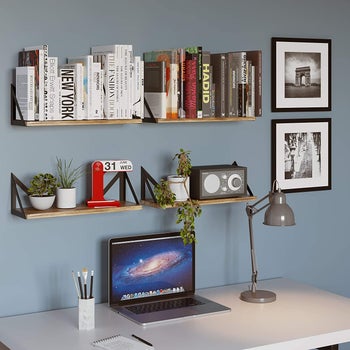 four sets of wall shelves holding books and decor above a desk