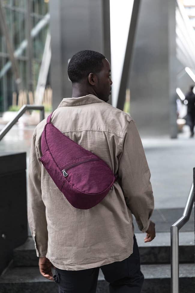 Man walking upstairs outdoors with a maroon crossbody bag